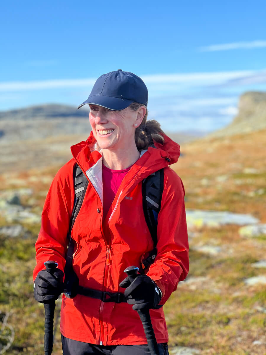 Smiling woman hiking with trekking poles in a mountainous landscape