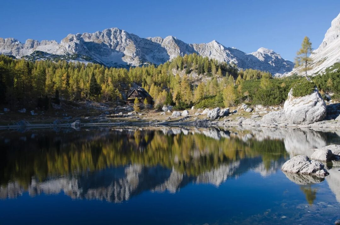 Alpine lake at the foot of rocky peaks and forest, scenic for hut-to-hut hiking in the mountains