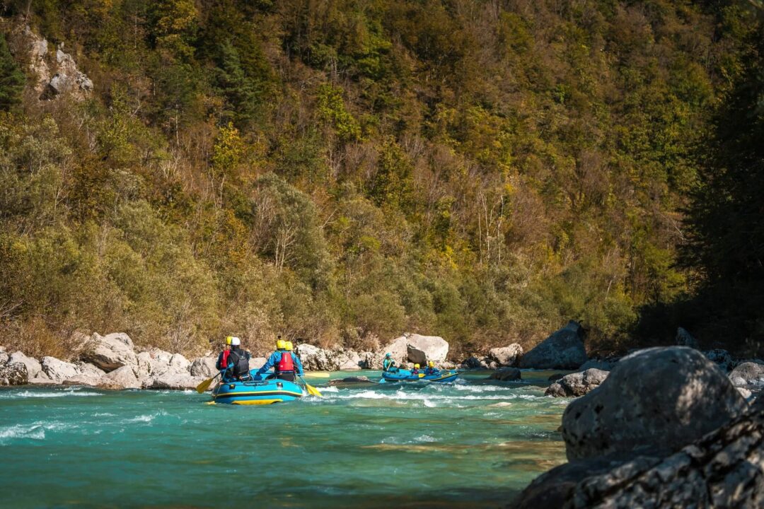 Women rafting on a green river between rocky shores in Croatia, surrounded by forested hills