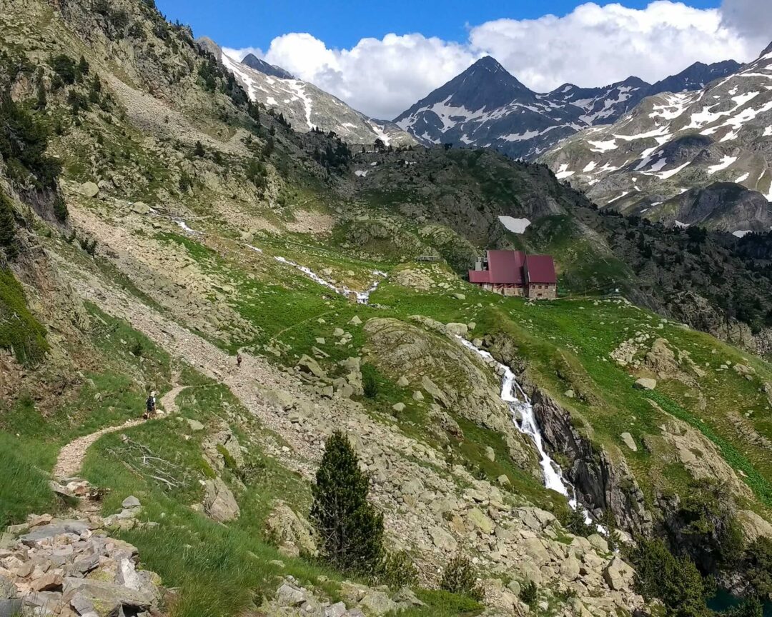 Hut-to-hut hiking route in the Spanish Pyrenees, with a mountain refuge hut in a valley