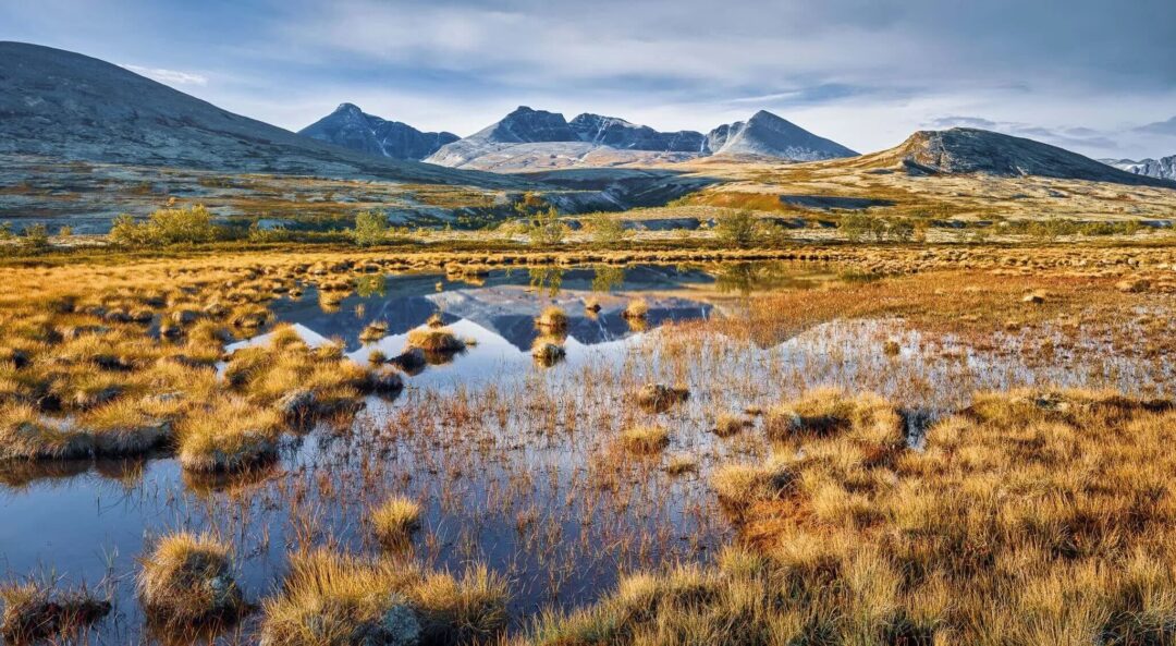 Norwegian valley landscape with small lakes and low mountains under a cloudy sky