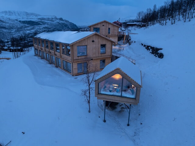 Snow-covered wooden lodge and cabins in Norway at dusk
