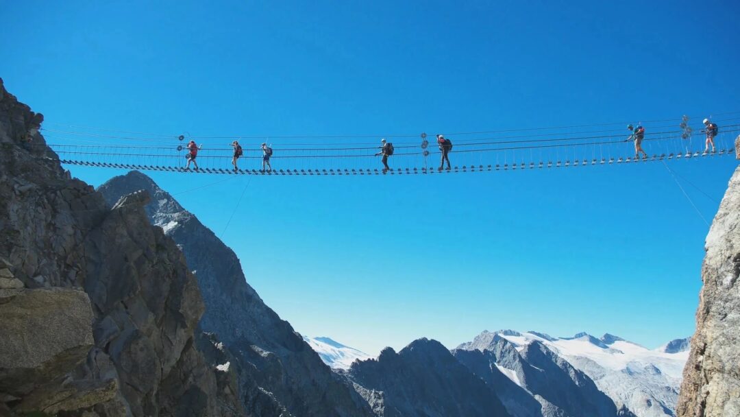 Women crossing a via ferrata rope bridge over a mountain gorge in the Dolomites