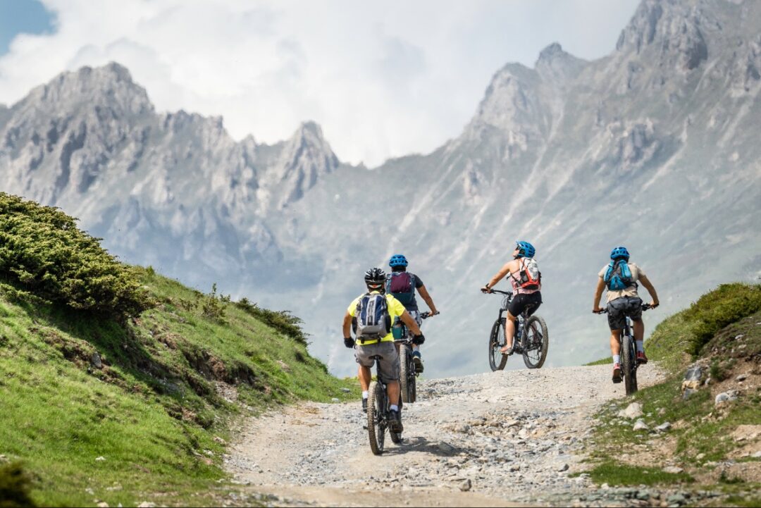 Women cyclists on gravel path riding e-bikes through North Macedonia’s mountain national park landscape