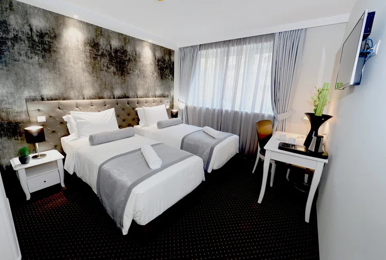 Hotel room with two made beds, bedside tables, and curtains, set up for a North Macedonia hiking stay