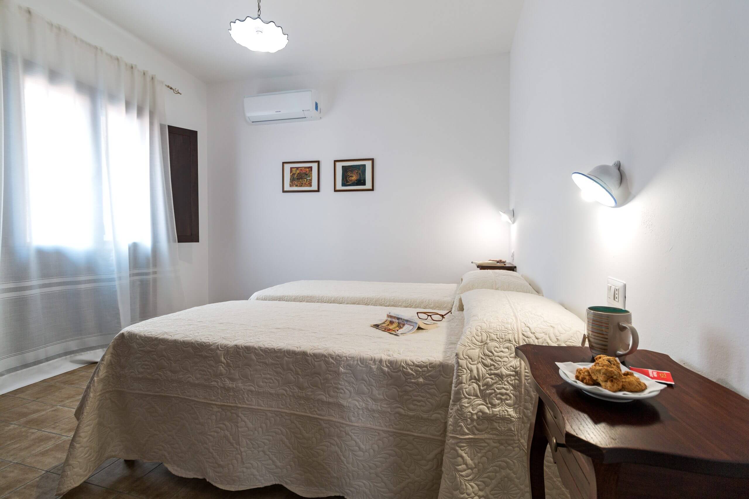 Bright hotel bedroom with double bed, bedside table, mug and wall lamp