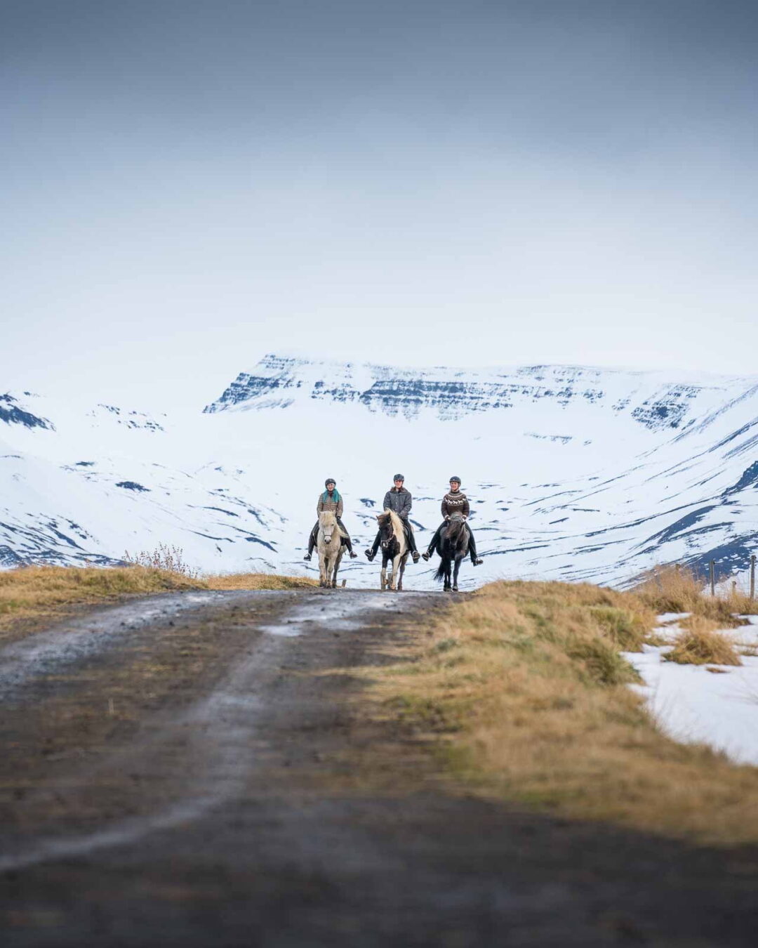 Women hiking a winter trail in North Iceland with snow-covered mountains in the background
