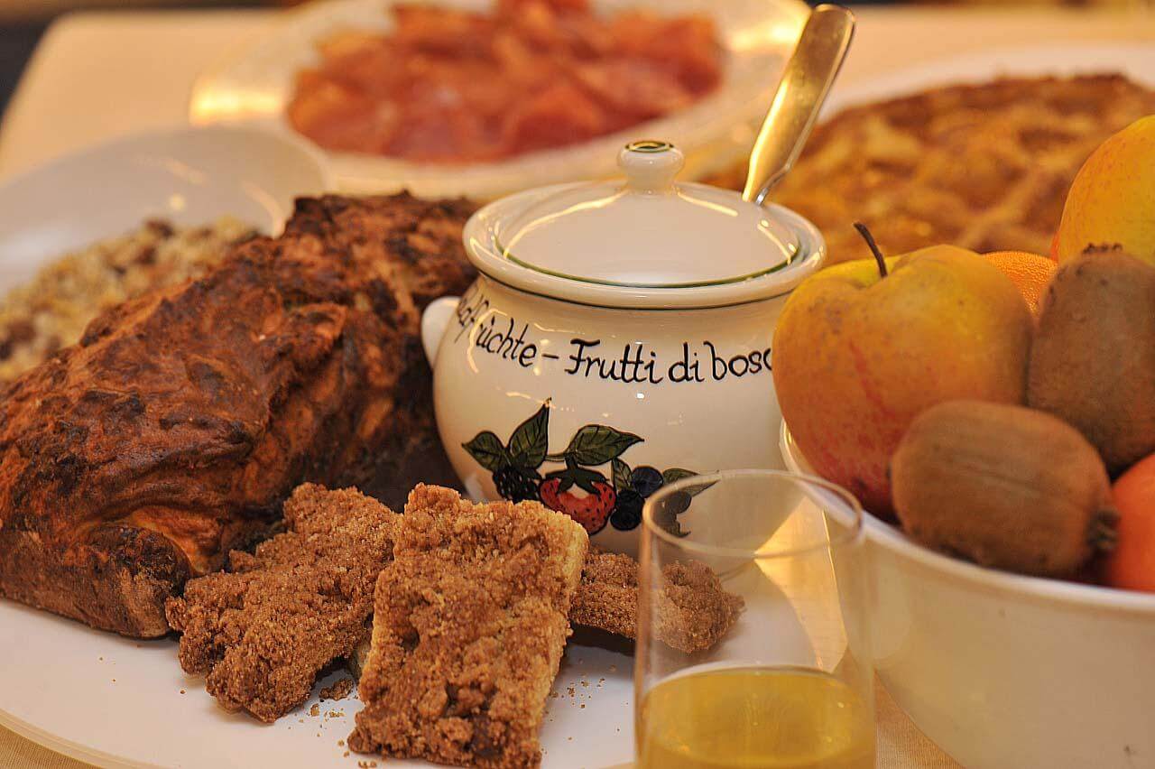 Plate of fried schnitzel and snacks with a teapot and fresh fruit on a dining table