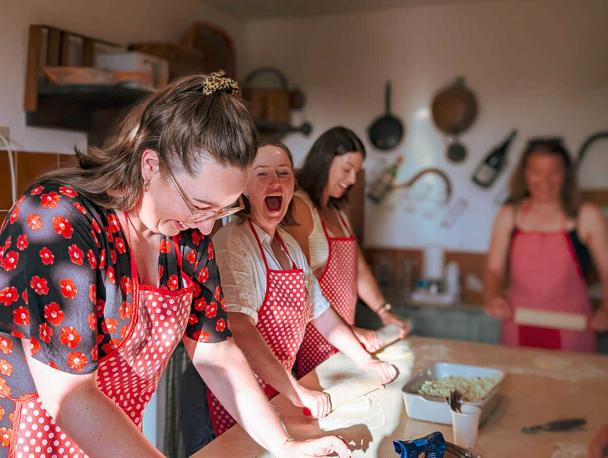 Women in aprons prepare food together in a kitchen during a Gutsy Girls adventure holiday