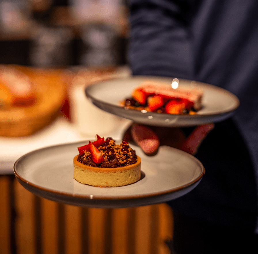 Strawberry tart dessert on a plate at a dining table, served with other appetisers in the background.