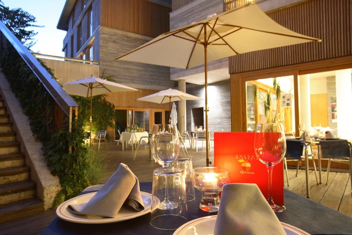 Outdoor dining terrace at a mountain hut, with patio umbrellas and neatly set tables for a meal