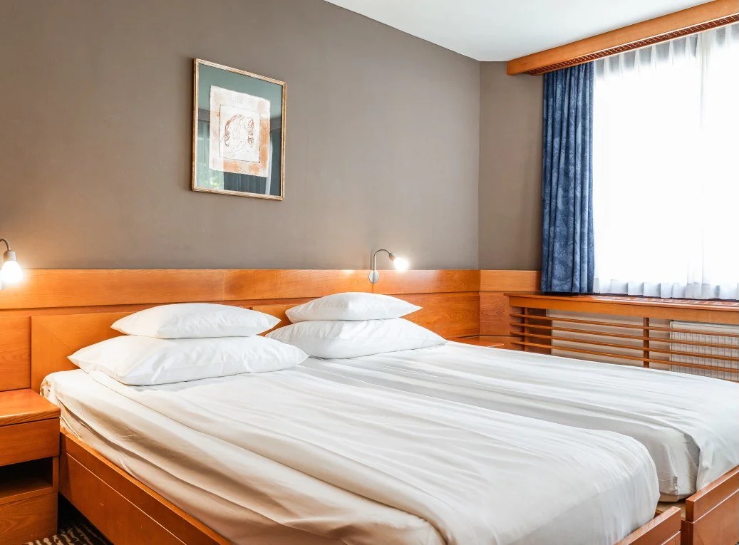 Double bed in a hotel bedroom with wooden headboard and bedside lamps