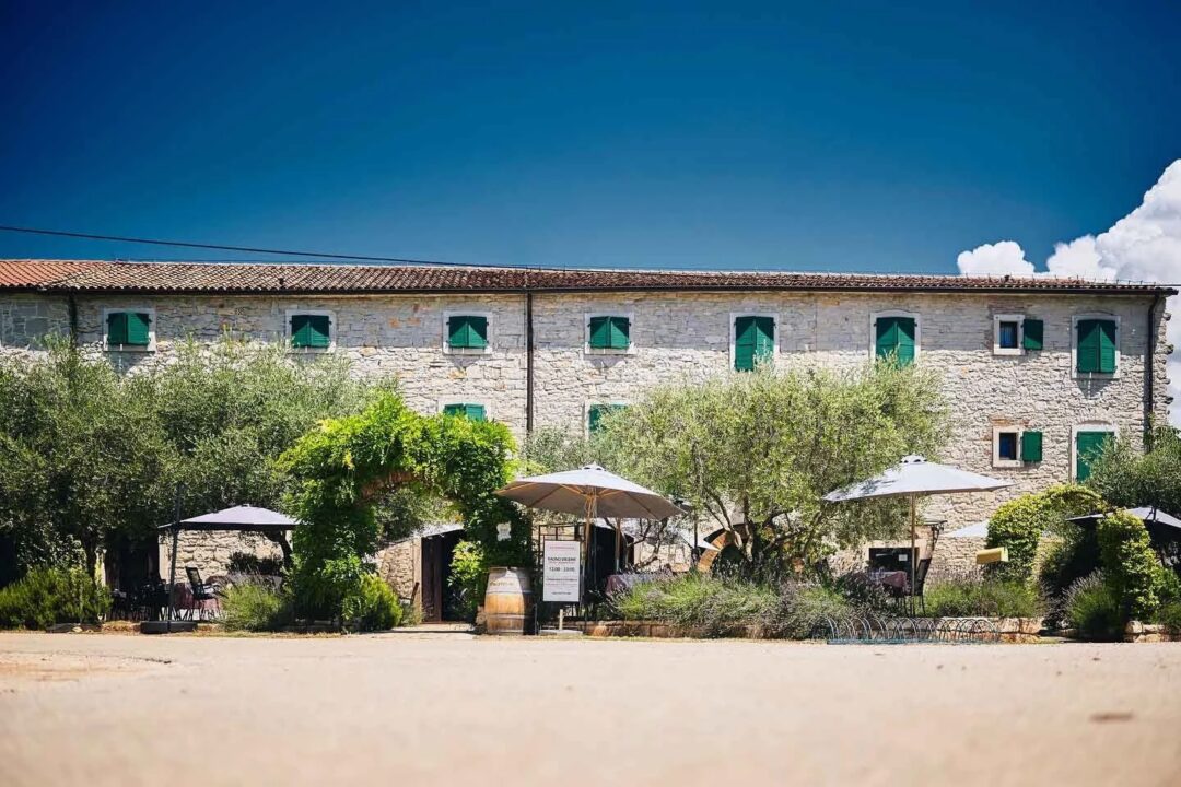Stone villa courtyard with outdoor seating and parasols beneath green shutters