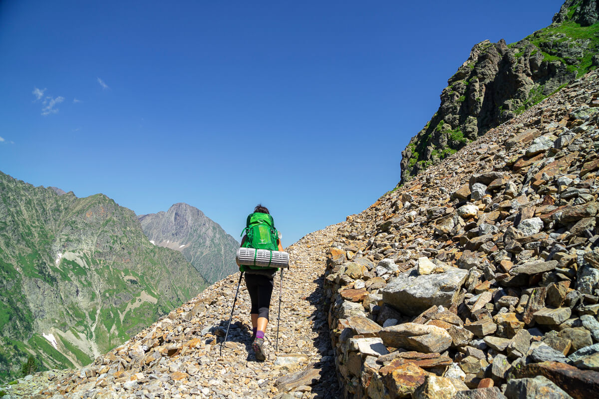 Women hiking along a rocky mountain path in the Spanish Pyrenees under a clear blue sky