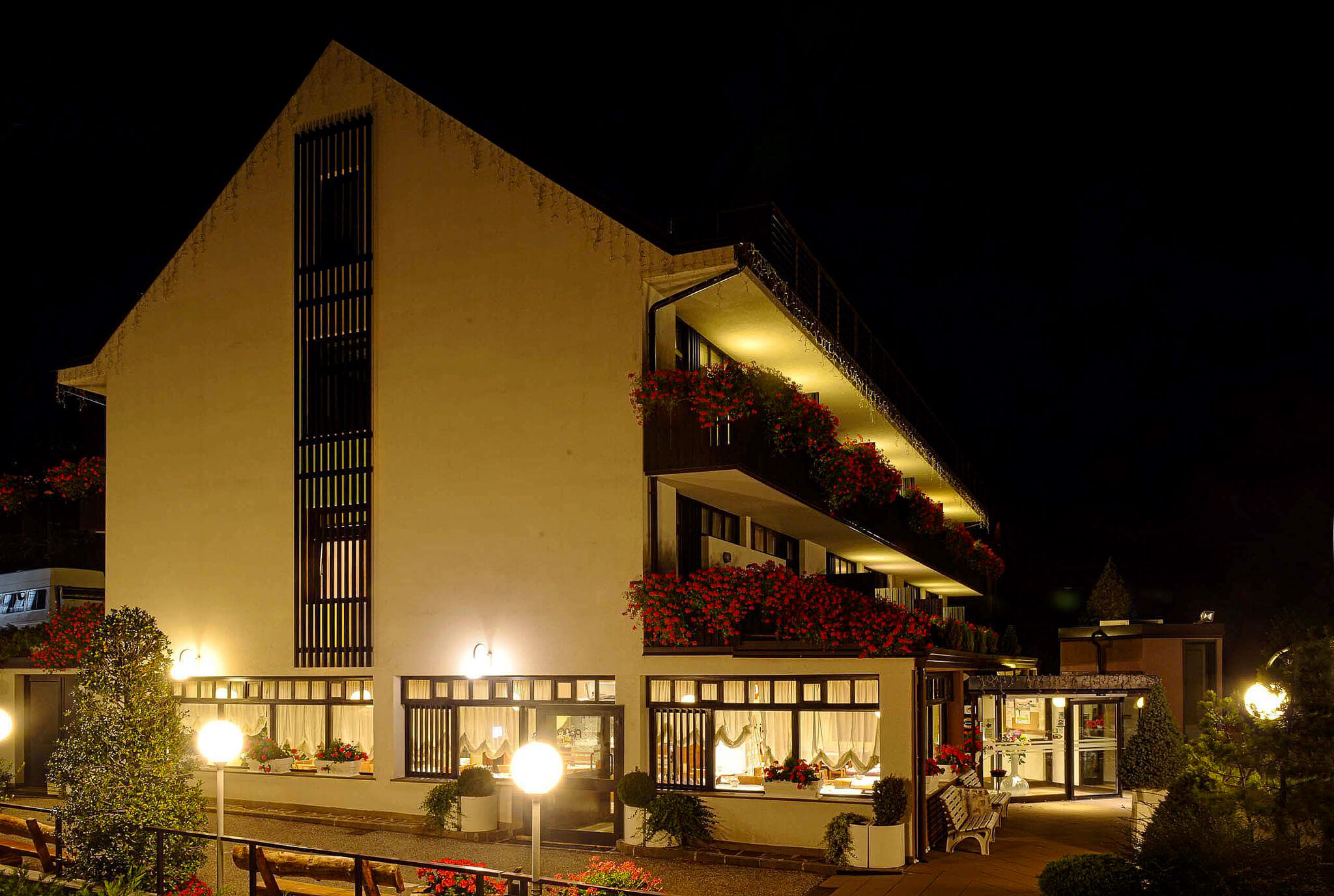 Illuminated alpine chalet exterior at night with warm lights and flower boxes