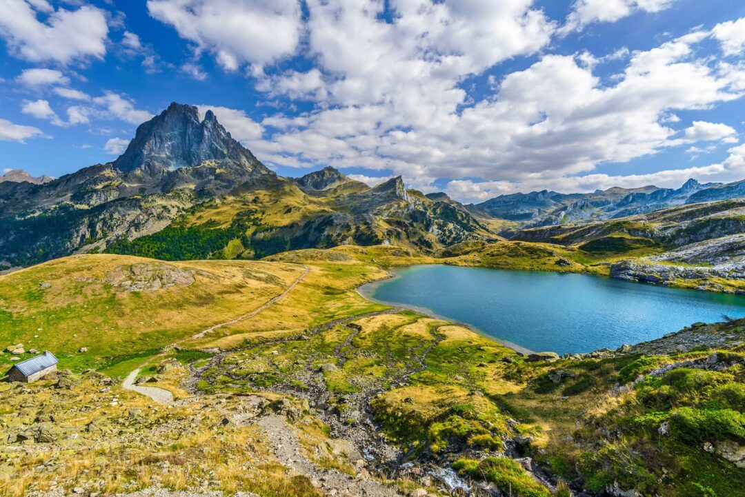 Mountain trail leading to a lake in the Spanish Pyrenees, with rocky peaks and summer clouds