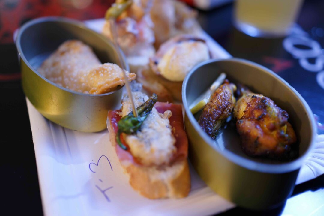 Grilled bites and bread served in camping bowls on a hut-style adventure table