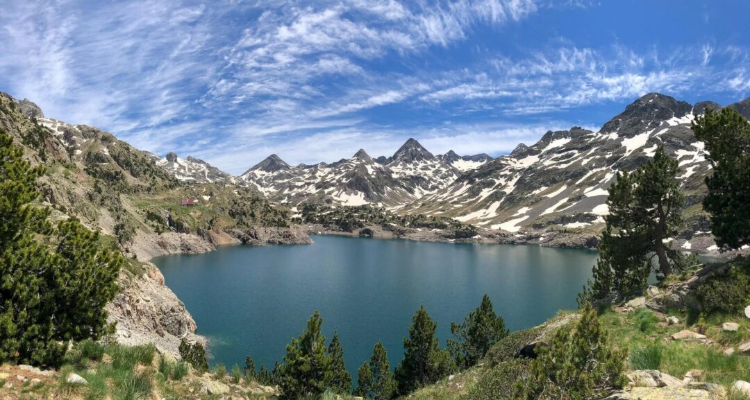 Scenic mountain lake in a rugged Pyrenees valley with snow-capped peaks and alpine trails