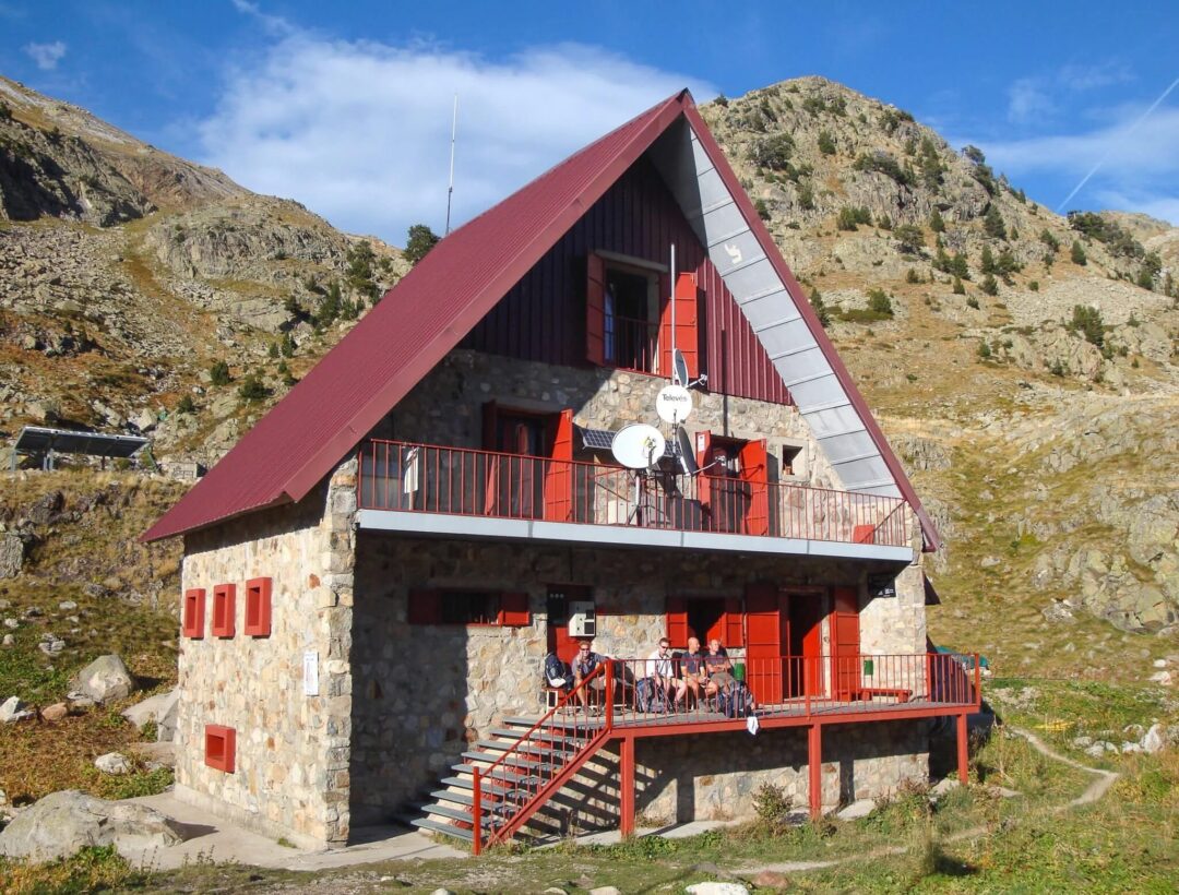 Mountain hut in the Spanish Pyrenees for hut-to-hut trekking adventure, with red balcony and exterior
