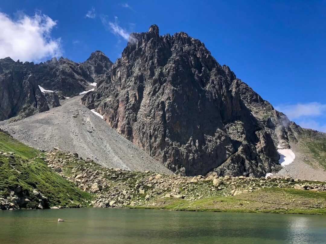 Mountain trail and alpine lake in the Spanish Pyrenees, with rugged peaks under a blue sky
