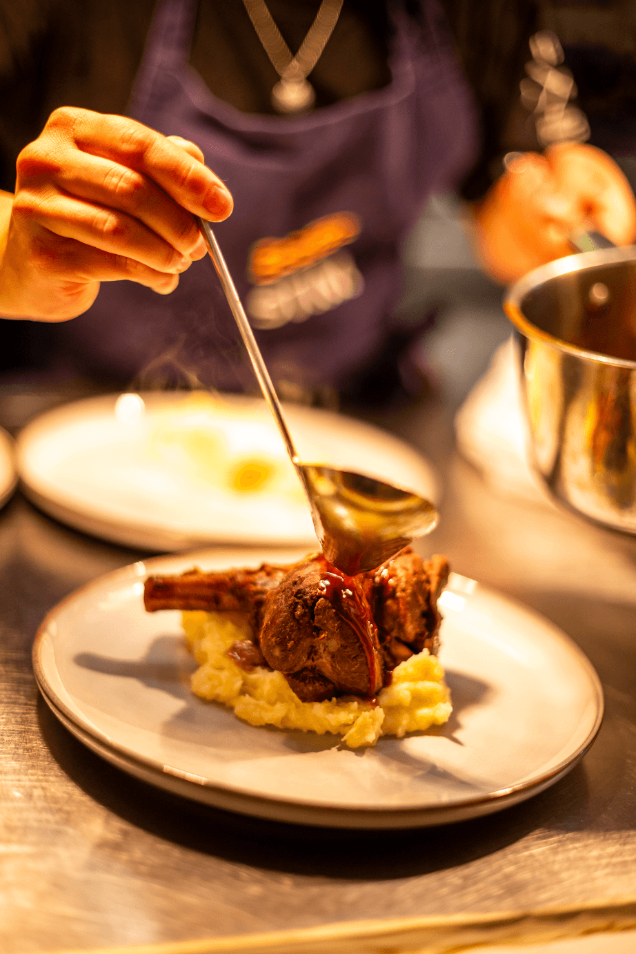 Woman serving a meatball dinner on a plate with a spoon, warm kitchen lighting