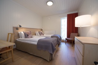 Double bedroom in a wilderness lodge with bed, desk and lamp, bright interior with large window