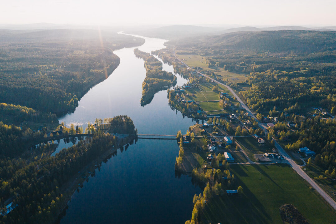 Aerial view of a winding river through forested valleys and fields in Sweden