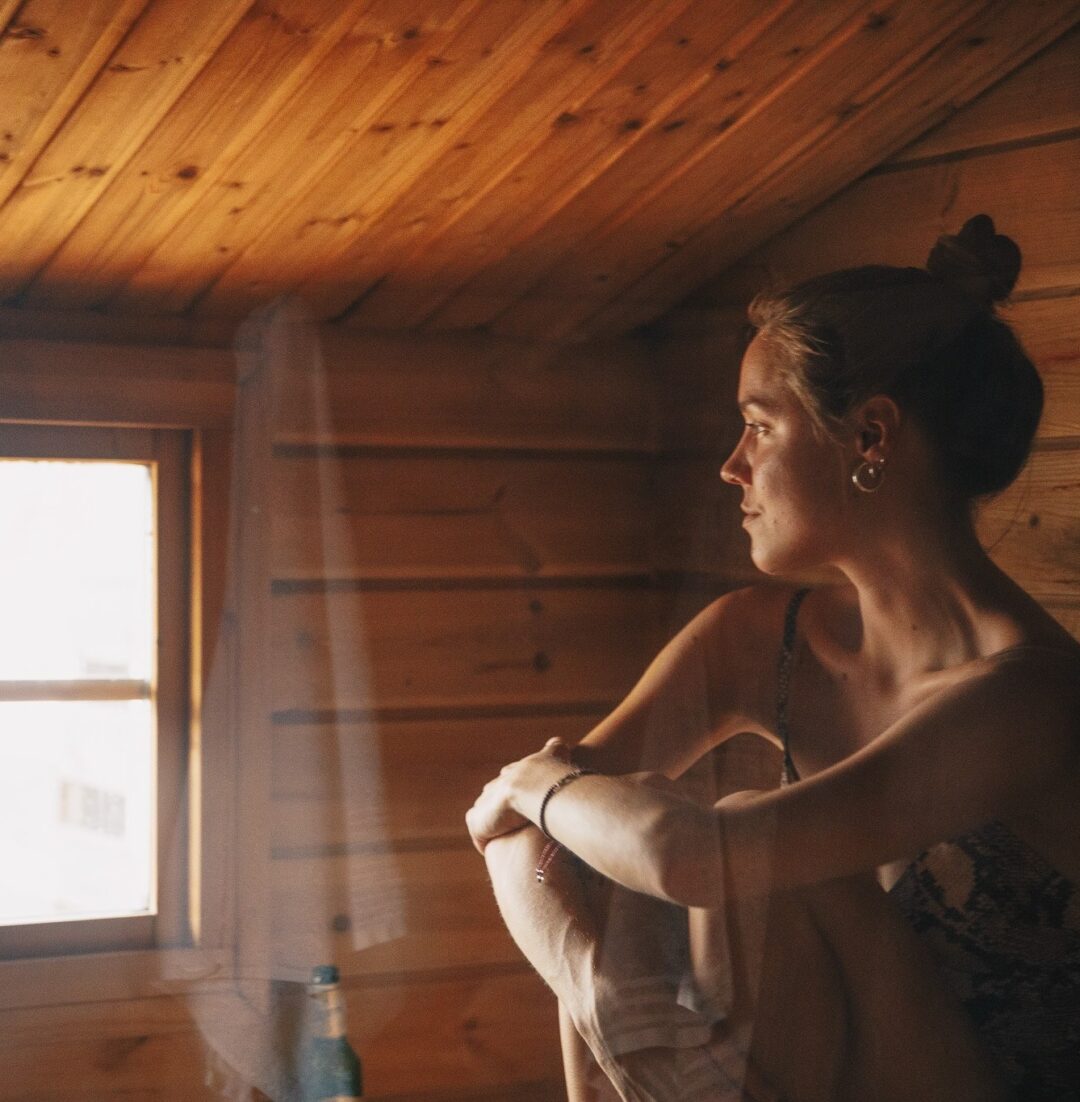Woman preparing outdoor clothing in a wooden cabin, Swedish Lapland wilderness adventure setting