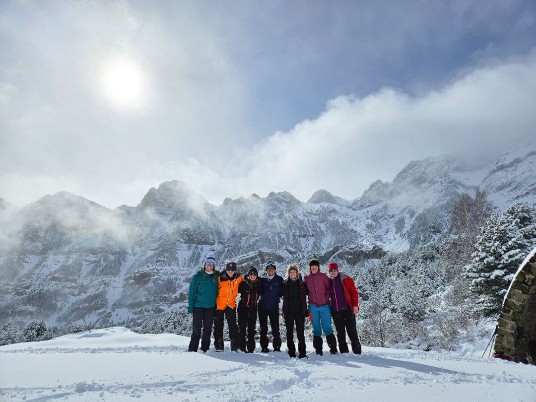 Women winter hikers standing together in a snowy mountain landscape under cloudy skies