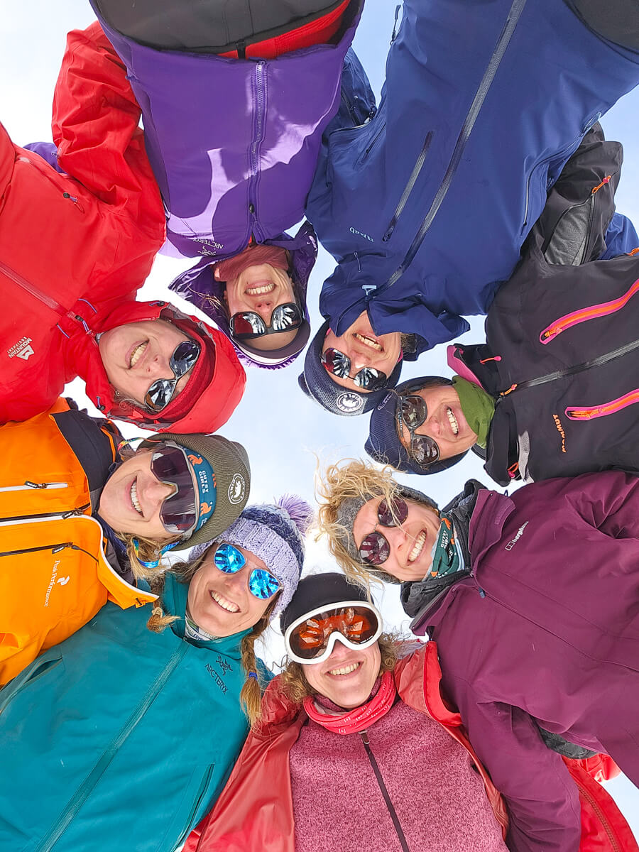 Women smiling in winter clothing and goggles in snowy mountains, ready for snowshoeing or winter hiking