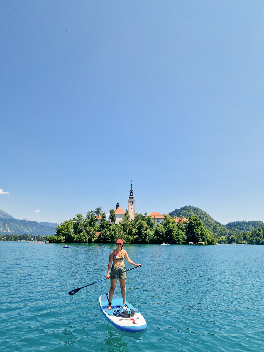 Woman SUP paddling on a lake in Slovenia with a church on an island in the background