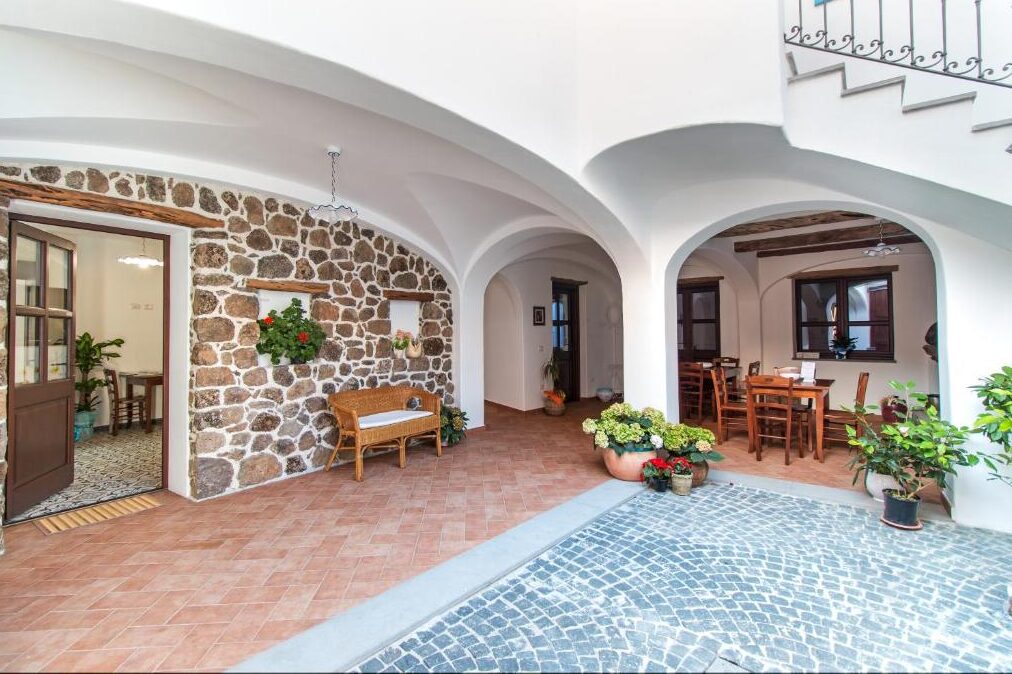 Courtyard with arched white walls, stone facade and a small tiled swimming pool in East Sardinia.