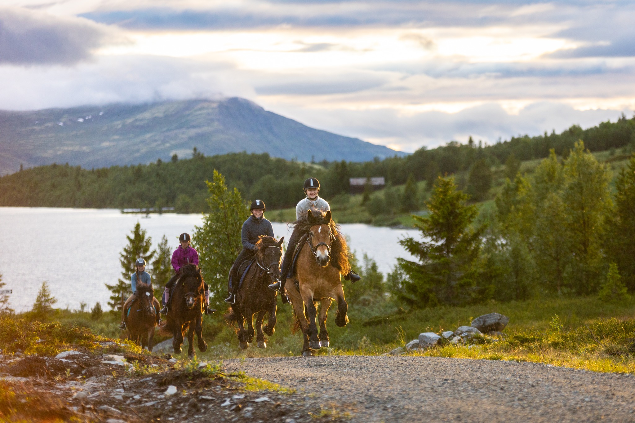 Women horseback riders on a Norway trail with a lake and mountains in the background