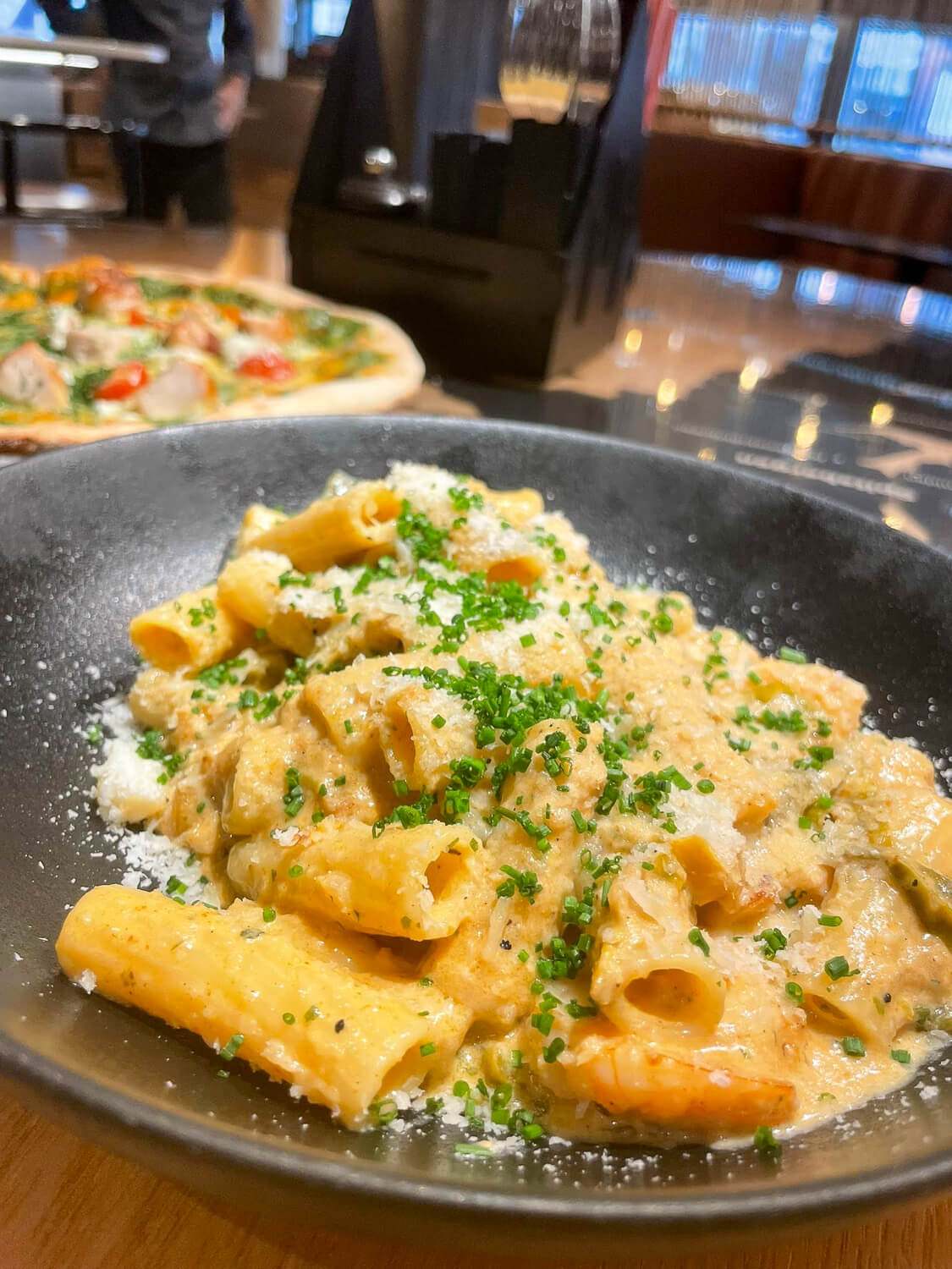 Plate of pasta with cheese and herbs in a restaurant, served as a meal for an outdoor adventure trip.