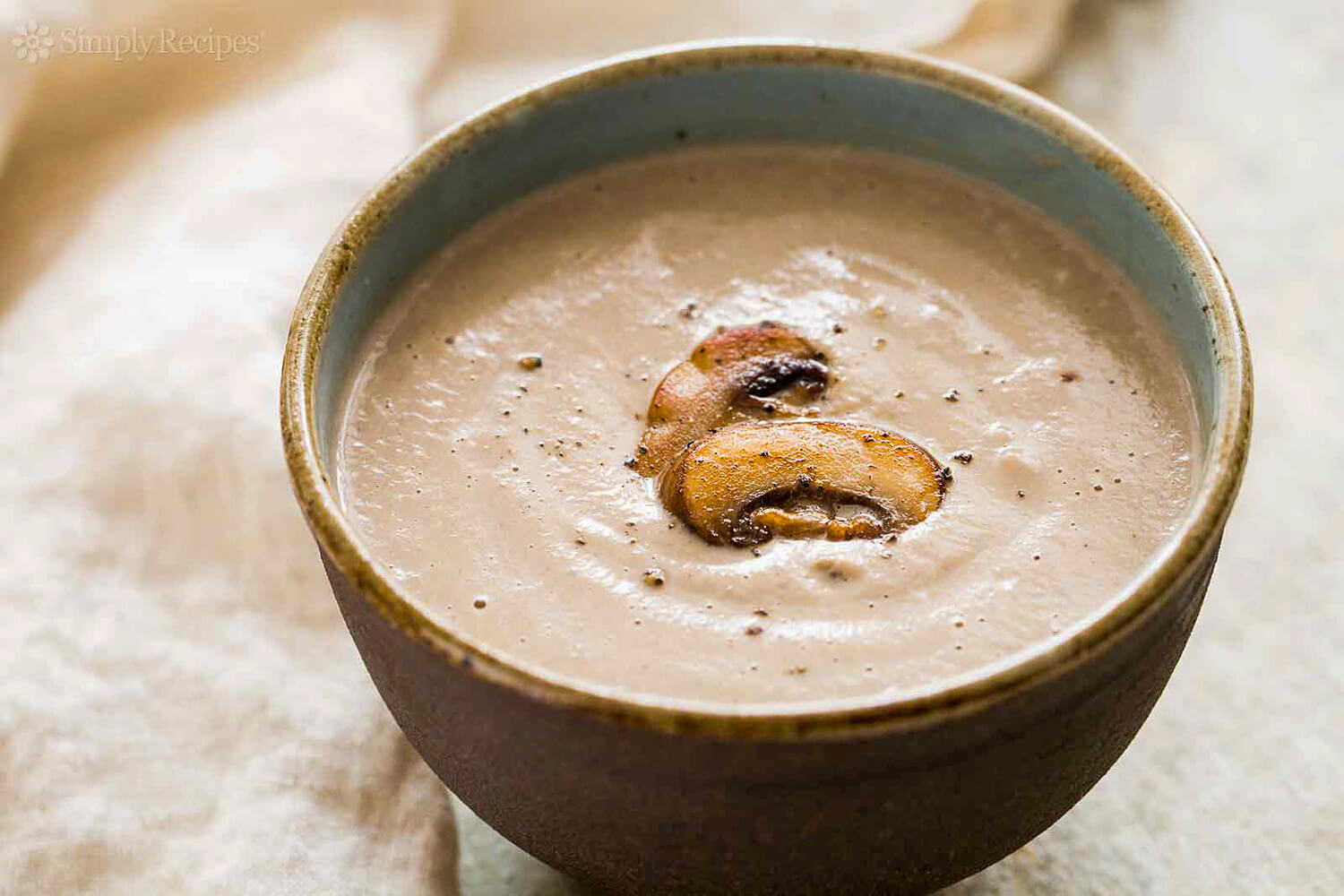 Bowl of creamy soup with a roasted meat slice in a winter meal setting