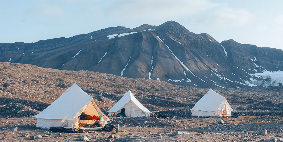 Camping tents in Arctic wilderness with snow-dusted mountains in Svalbard, Norway