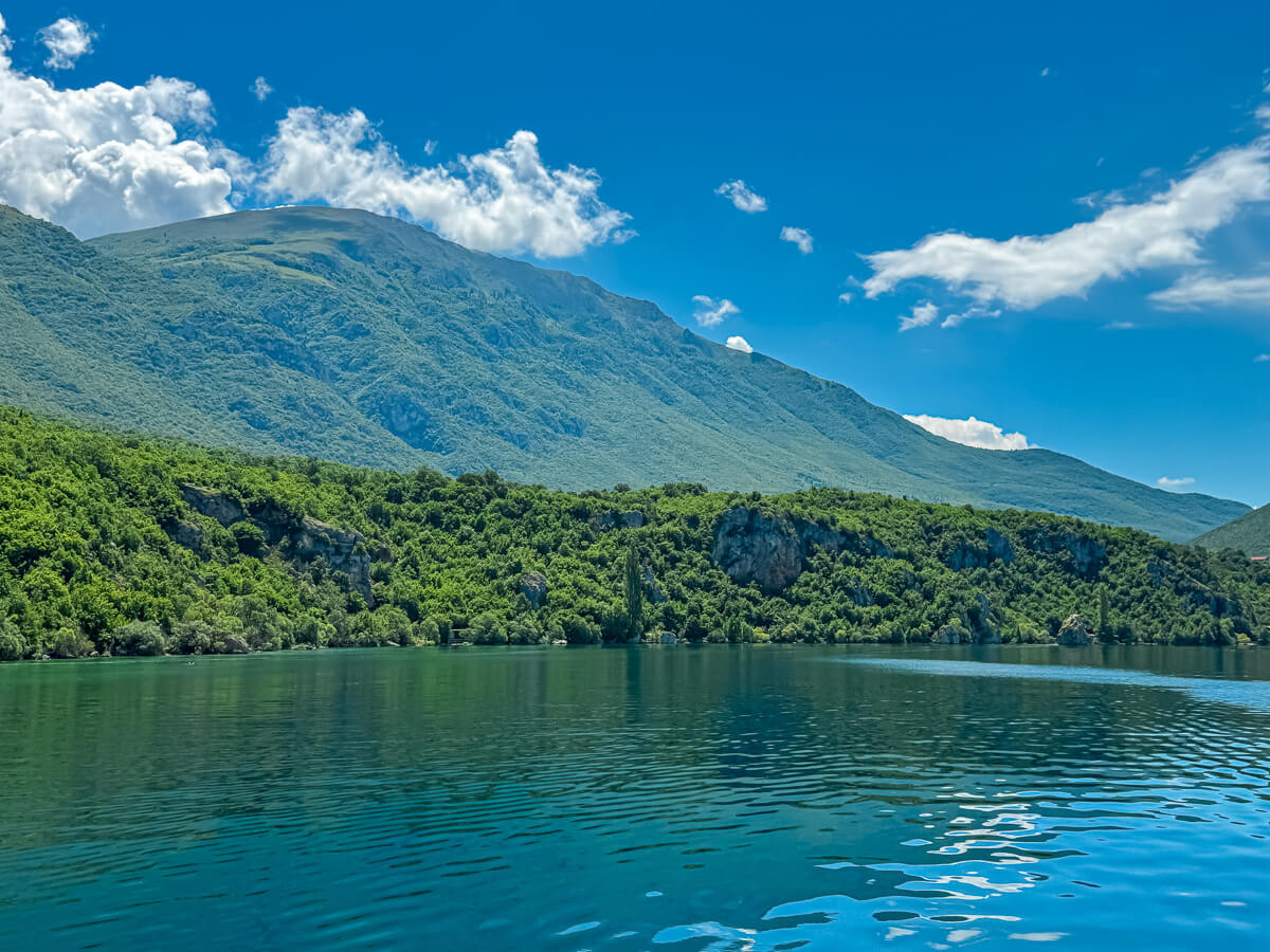 Lake Ohrid shoreline with calm water and green mountains under a blue sky in North Macedonia