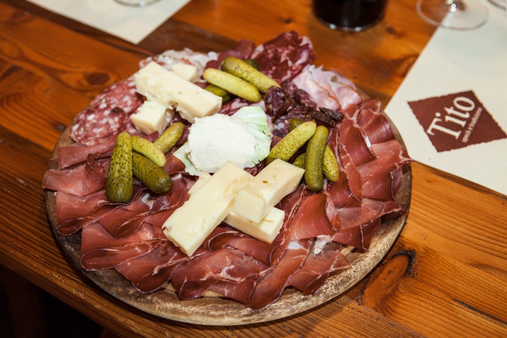 Antipasto board with cured meats, cheese and pickles, with card reading “Lito”.