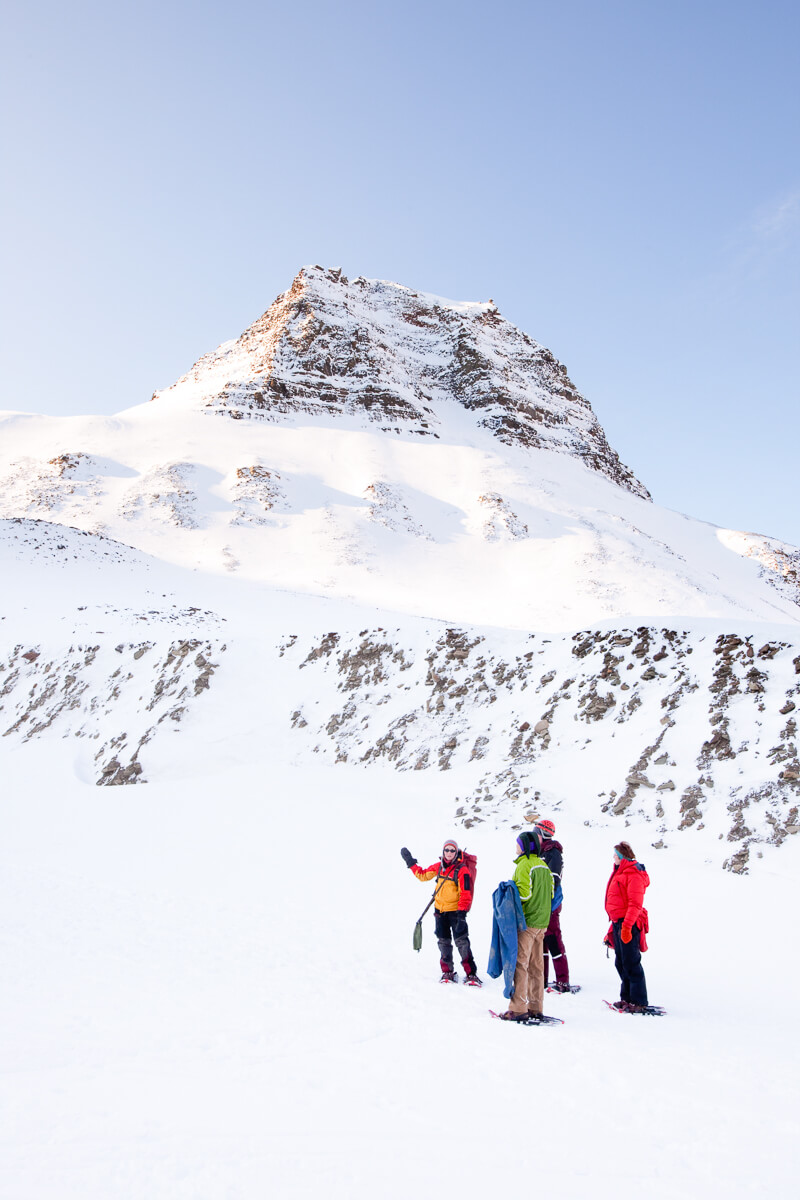 Women in winter clothing trekking on a snowy mountain slope under clear skies in the Alps