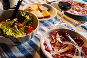 Dinner table with pizza, pasta, vegetables and a glass of red wine