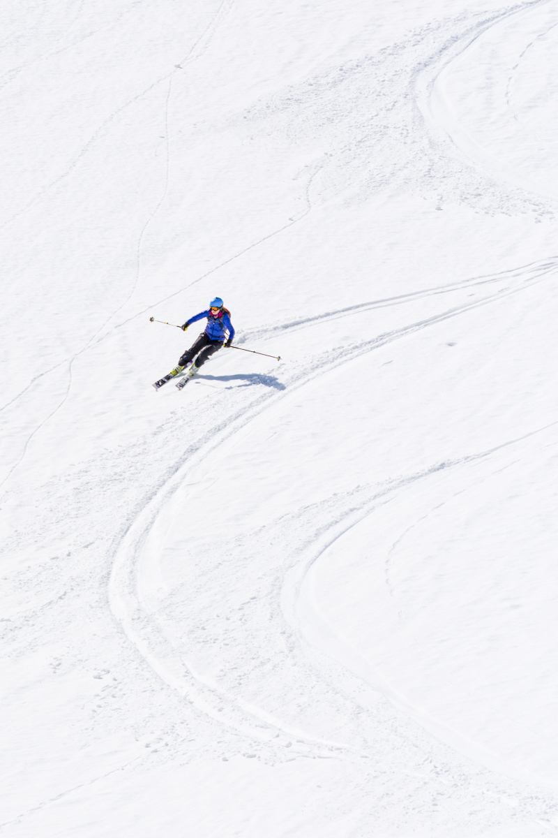 Woman ski touring downhill on snowy mountain slopes
