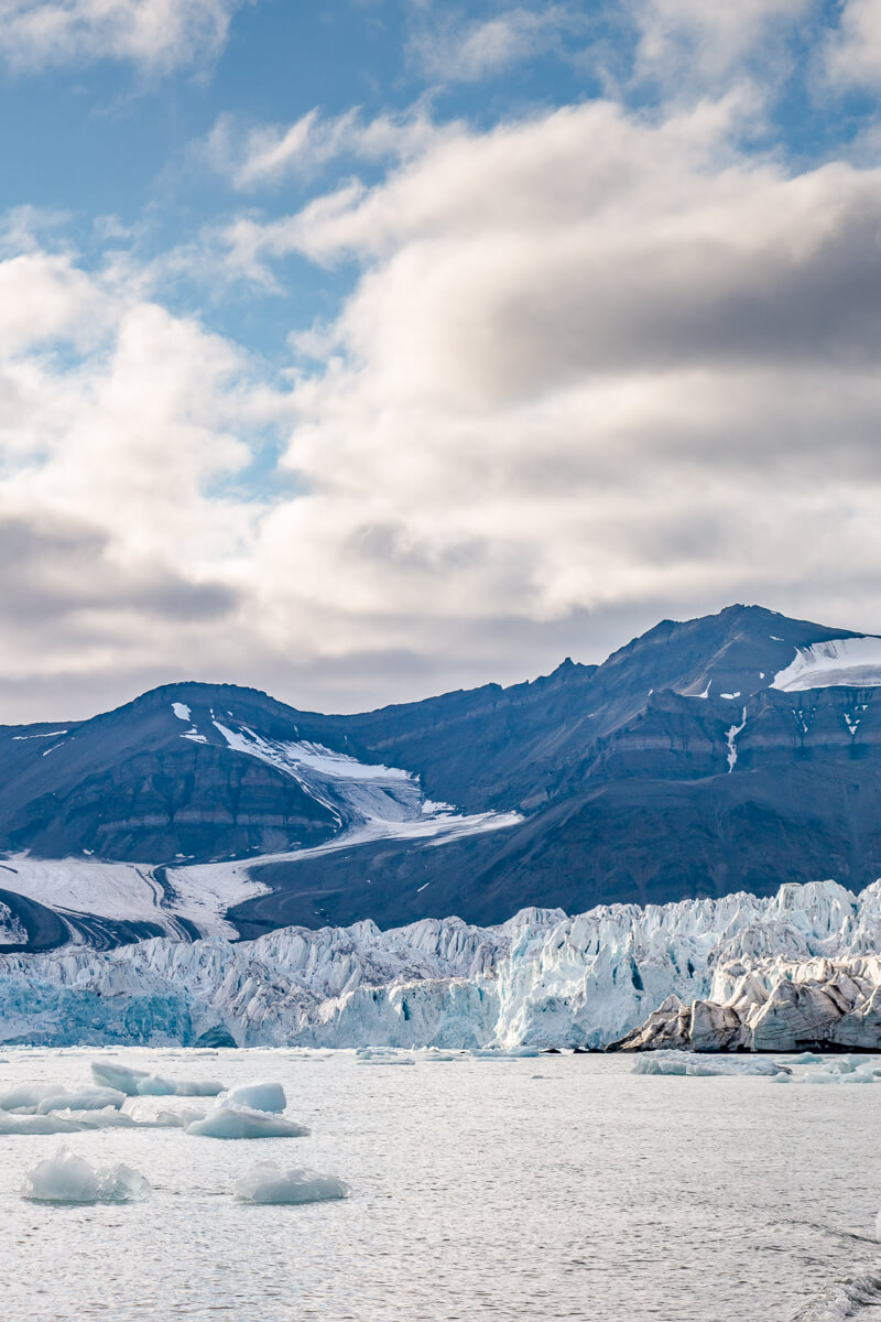 Glacier and icebergs with mountain peaks in Svalbard, Arctic wilderness landscape