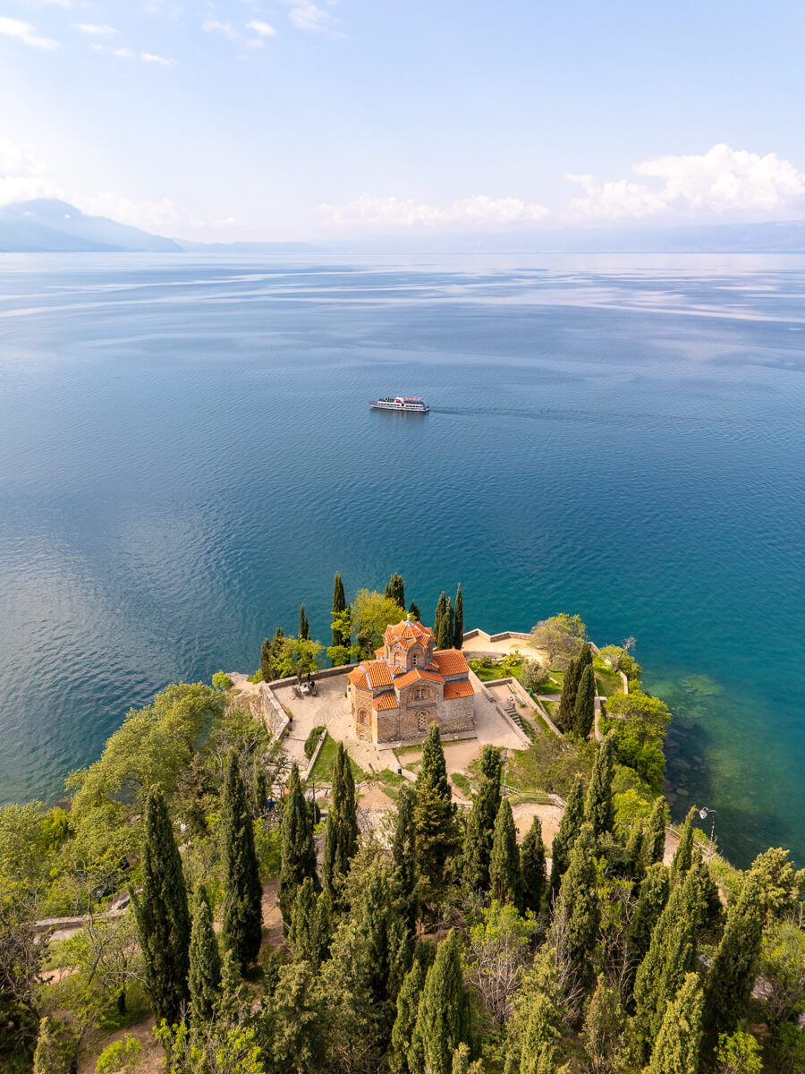 Lake Ohrid in North Macedonia with a lakeside monastery and small boat on calm water