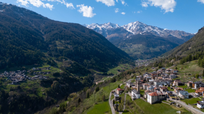 Aerial view of a village in the Dolomites, Italy, with surrounding alpine mountains and valleys.