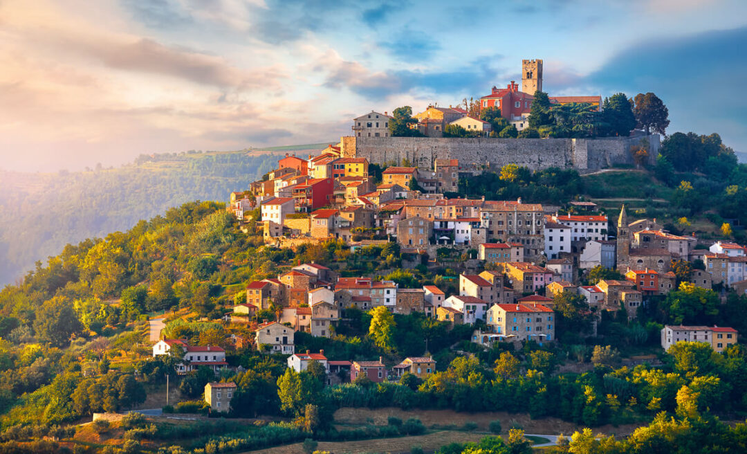 Hilltop riverside village with historic buildings and church at sunset