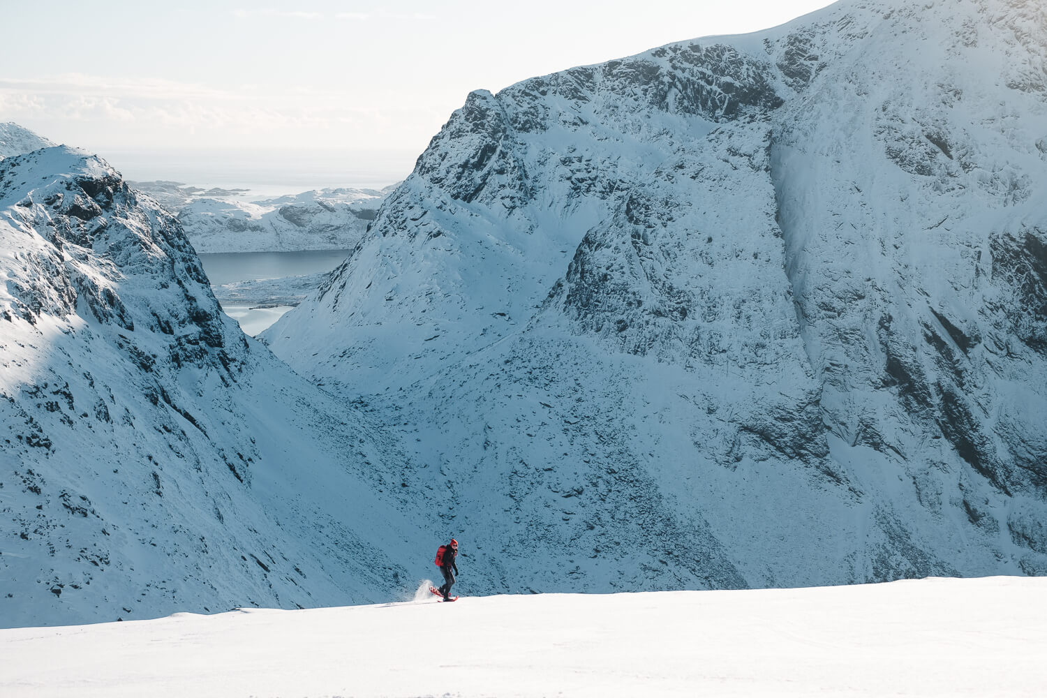 Woman skiing on a snow-covered mountain overlooking a fjord landscape