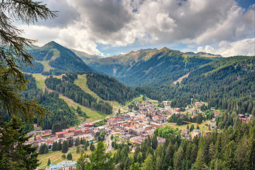 View over a Dolomites valley town, with alpine peaks and forest slopes
