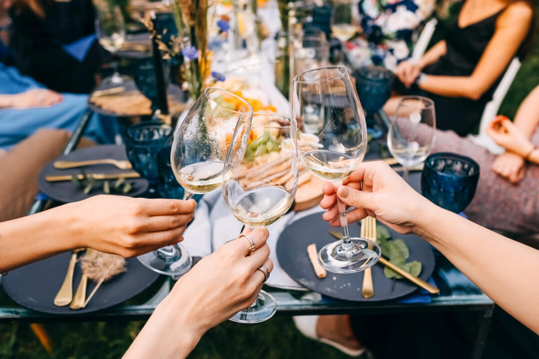 Women clinking wine glasses at an outdoor dinner on a multi-activity holiday.