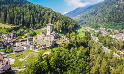 Aerial view of a Dolomites village in Italy, surrounded by green valley and mountain scenery.