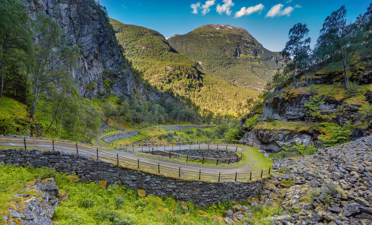 Jotunheimen, Norway: mountain valley with river, winding road and fenced paths in a hiking landscape